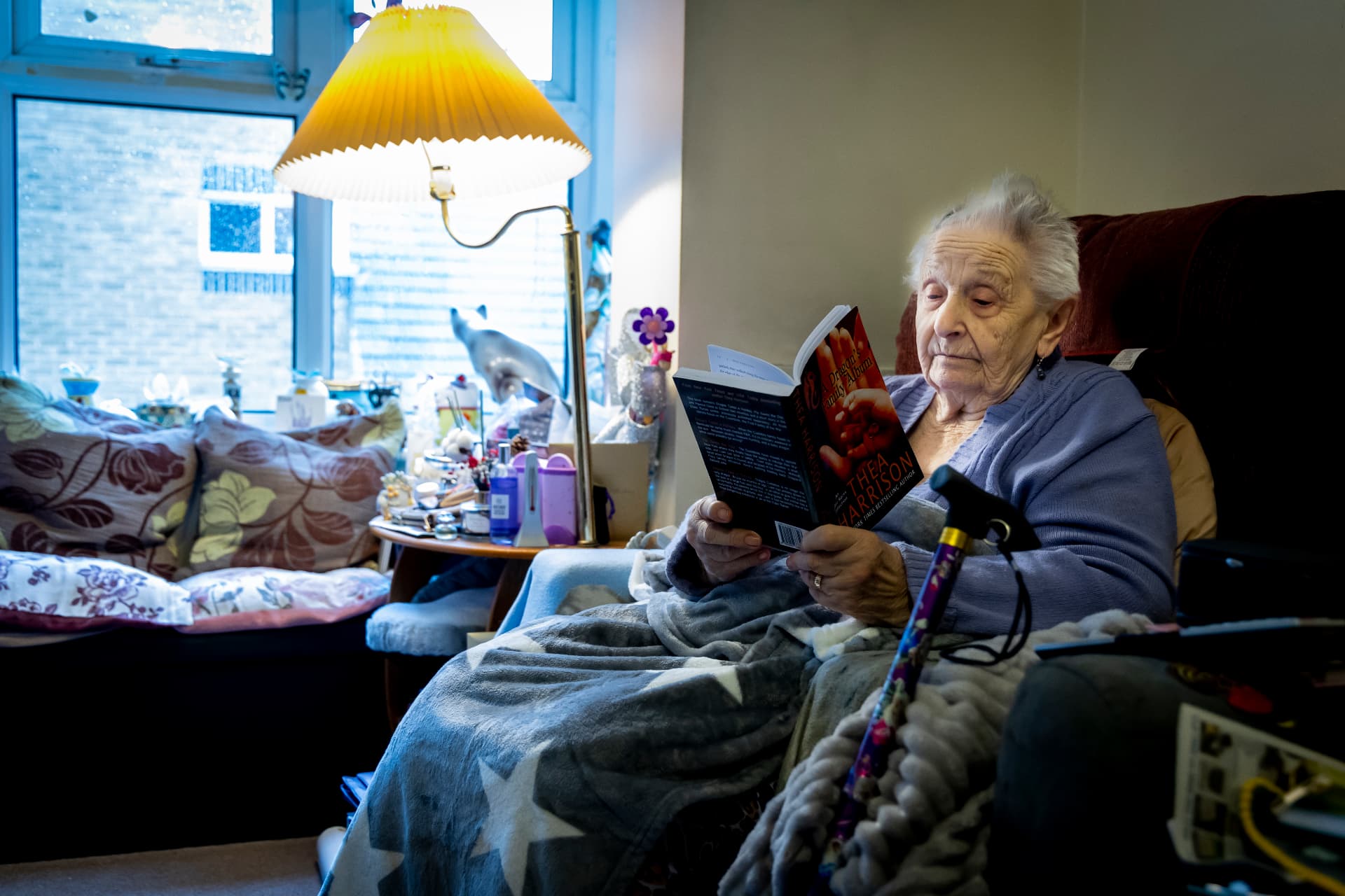 An older woman reading alone in her armchair at home, the sort of person our companionship visits are for
