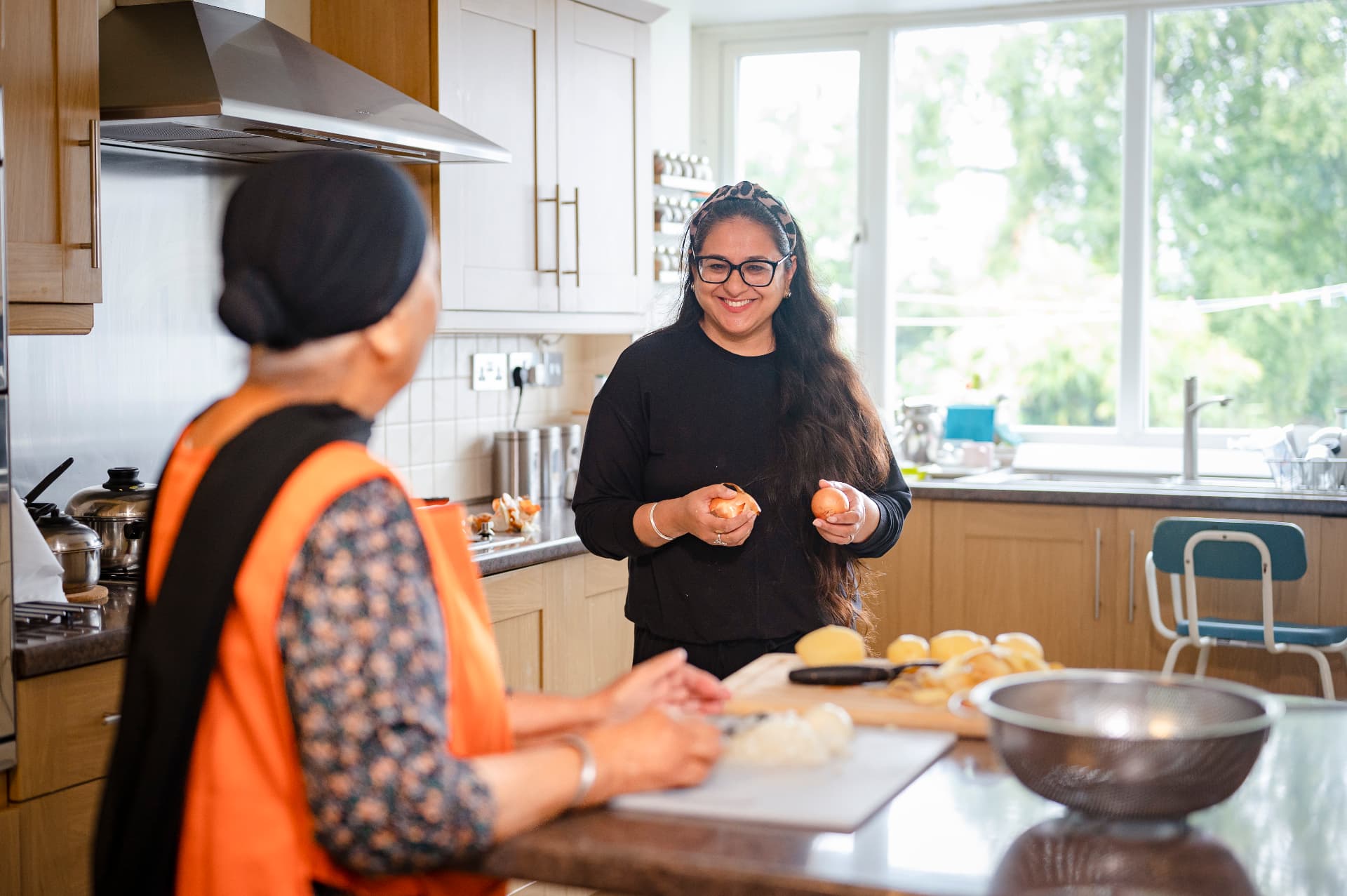 A companion and an older woman talking and preparing food together in her kitchen