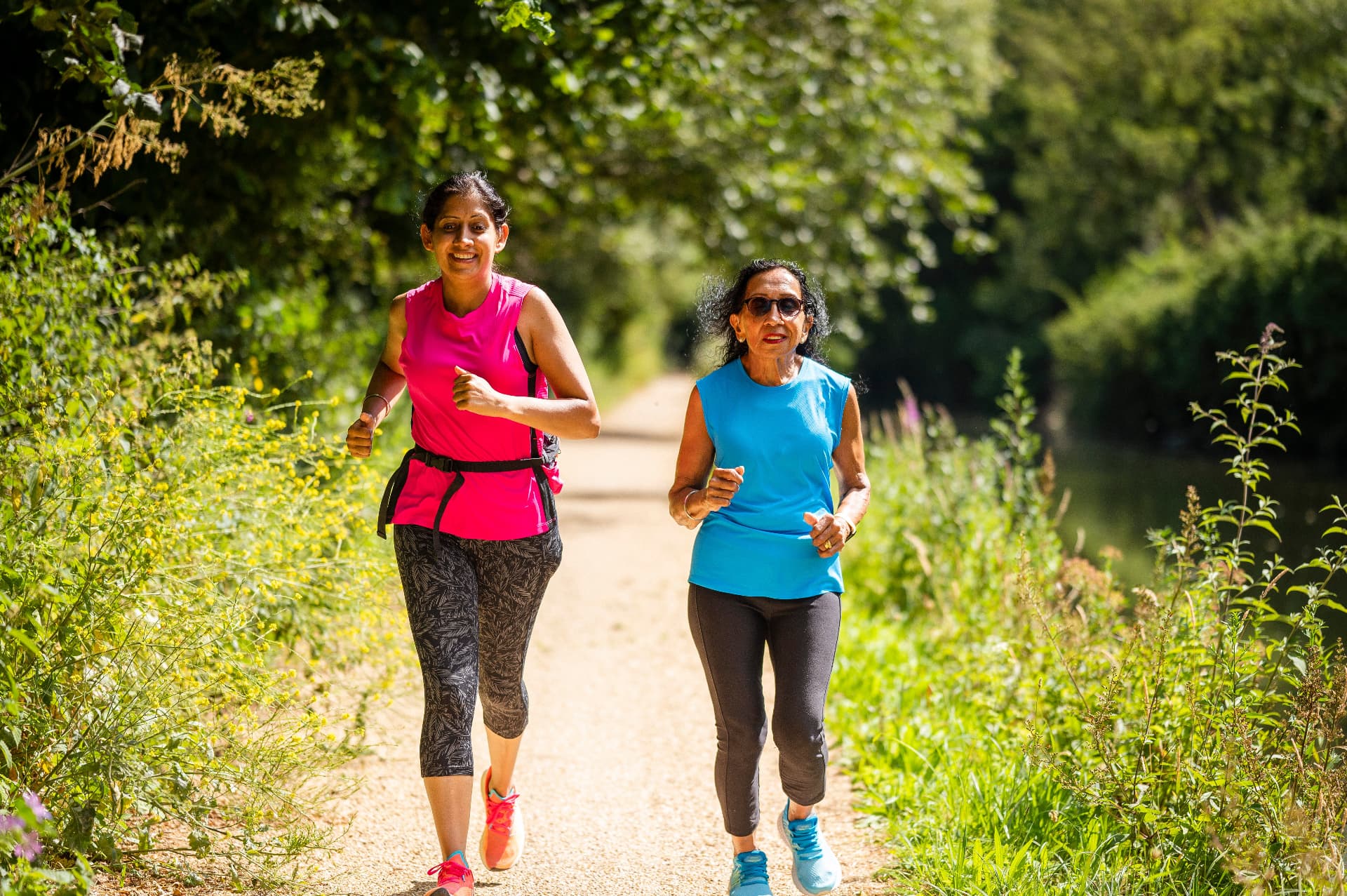 An older woman walking on a riverside path with her companion on a visit out and about