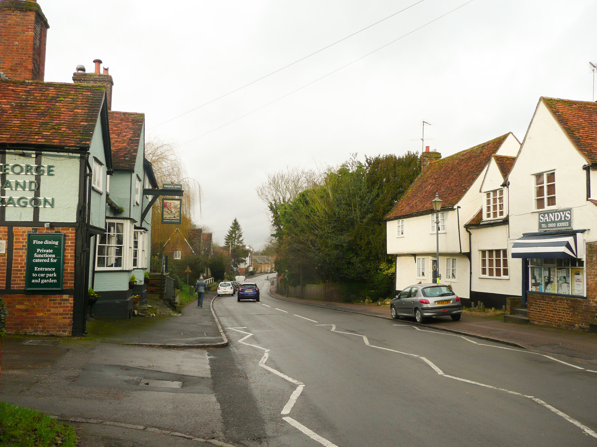 The village road through Watton-at-Stone beside local shops and the George and Dragon